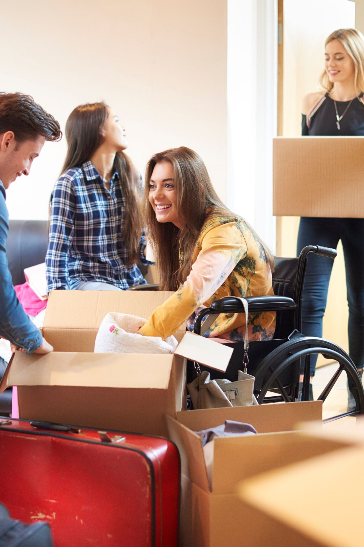 4 happy young friends moving into an apartment full of boxes